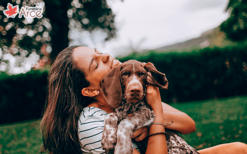 Mulher abraçando seu cachorro em um parque - animal de estimação